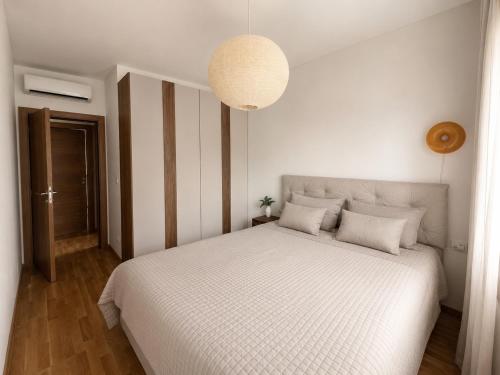 a bedroom with a large white bed with a lamp at Valeri Lux Becici in Rafailovici
