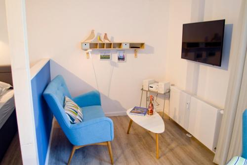 a small room with a blue chair and a table at Appartements Villa Schwanenteich in Fehmarn
