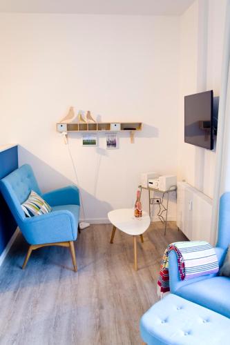 a living room with two blue chairs and a table at Appartements Villa Schwanenteich in Fehmarn