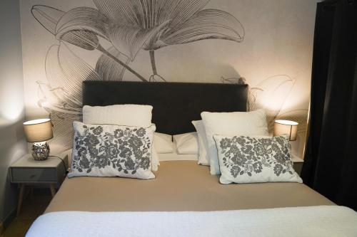 a bedroom with a bed with two pillows and a mural at Logis Hôtel Restaurant Le Domaine de l'Eau Vive in Largentière
