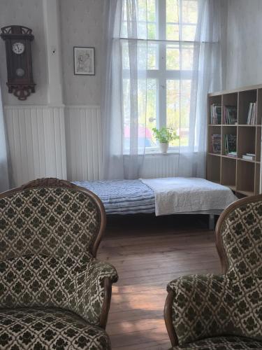 a bedroom with a bed and two chairs and a window at Skärvsta gamla skola in Sollefteå