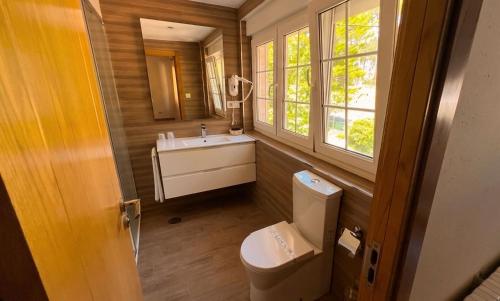 a bathroom with a toilet and a sink and a window at Hotel Restaurante Playa de Estorde in Cee