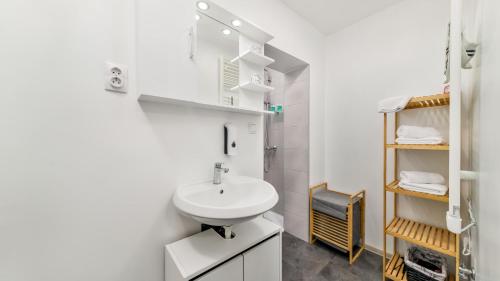 a white bathroom with a sink and a shower at Apartman Grey in Jastrebarsko