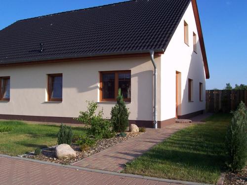 ein weißes Haus mit schwarzem Dach in der Unterkunft Ferienwohnung im Ostseeblick in Wismar