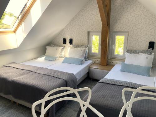 two beds in a room with two chairs and windows at Villa Aronia pokoje z aneksem kuchennym , parking bezpłatny in Ustka