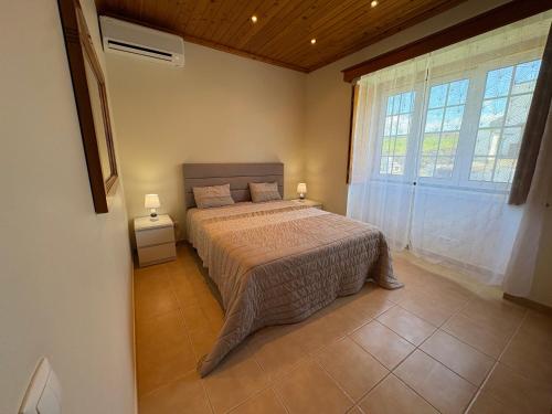a bedroom with a bed and a large window at Retiro da Ribeira in Angra do Heroísmo