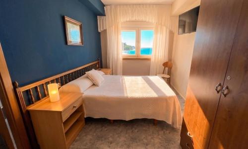 a small bedroom with a bed and a window at Hotel Restaurante Playa de Estorde in Cee