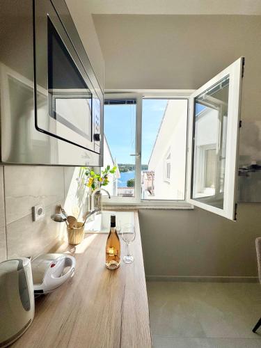 a bottle of wine on a wooden table in a room with windows at Illyrian Resort in Milna