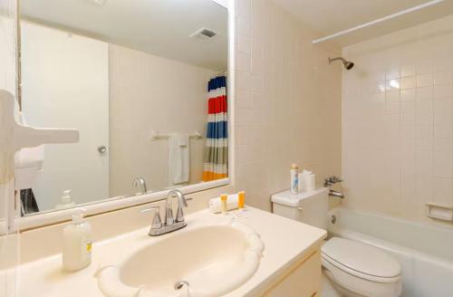 a bathroom with a sink and a toilet and a mirror at Sea Palm G in Fort Walton Beach