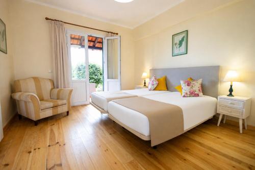 a bedroom with a large white bed and a chair at Casa da Tia Clementina in Santana
