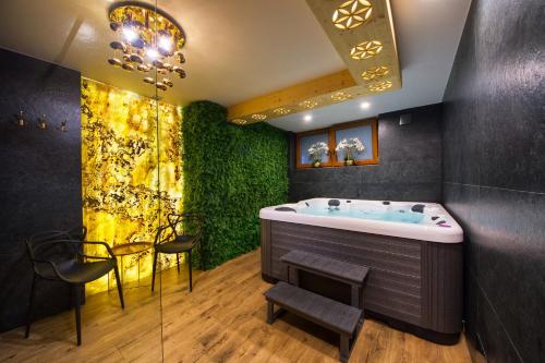 a bathroom with a tub and a green wall at Rezydencja Skibówki Apartamenty Domki Jacuzzi in Zakopane