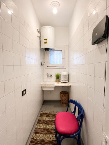 a small bathroom with a red chair and a sink at NubaNest GuestHouse in Aswan