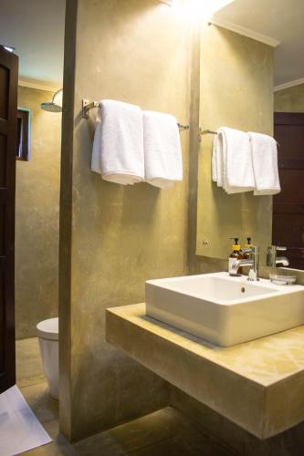 a bathroom with a sink and a toilet and towels at Rodrigo House in Colombo
