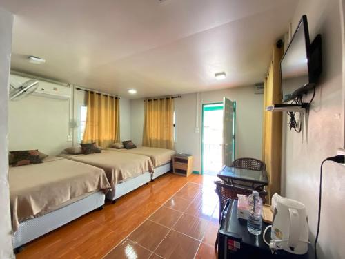 a bedroom with two beds and a television in it at Patcharin Home Stay in Ko Yao Yai