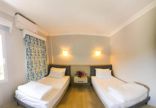 two beds in a small room with white sheets at Merve Apartments, your home from home in central BODRUM, street cats frequent the property, not all apartments have balconies , ground floor have terrace with table and chairs in Bodrum City