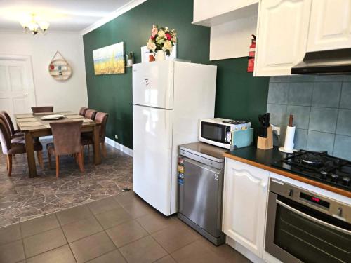 a kitchen with a white refrigerator and a table at Whispering Woods Pool Sauna in Maryborough