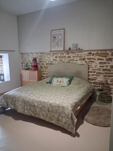 a bedroom with a bed and a brick wall at La grange famille in Tournans