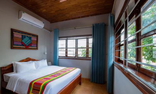 a bedroom with a bed and some windows at Tada Moc Chau - Villa & Local Kitchen in Mộc Châu