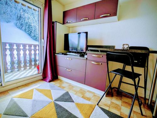 a room with a desk with a chair and a television at Les Portes du Soleil Studio in Le Biot