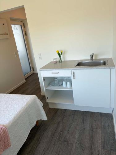 a white bathroom with a sink and a bed at South Harbour Studios in Vordingborg