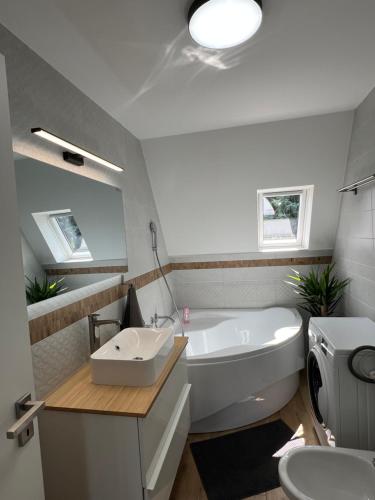a bathroom with a tub and a sink and a toilet at Pool & Chill Balaton in Balatonvilágos