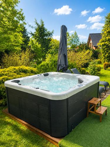 a hot tub in a yard with an umbrella at Serenity Garden Villas - Polanica-Zdrój in Stary Wielisław