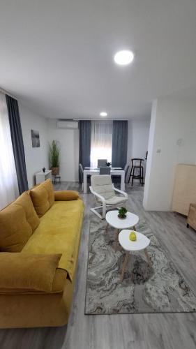a living room with a yellow couch and a table at SAMI APARTMAN in Niš