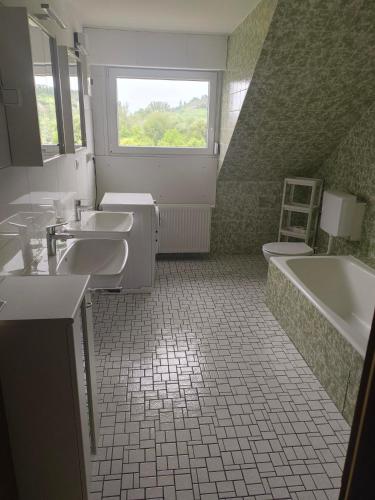 a bathroom with three sinks and a tub and a window at Inselappartement in Niederwerth