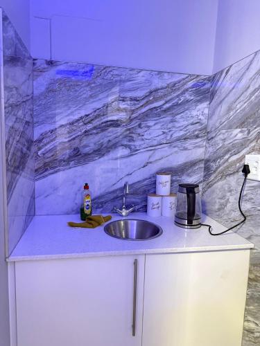 a kitchen counter with a sink and a marble wall at Deluxe Nest - Windhoek in Windhoek