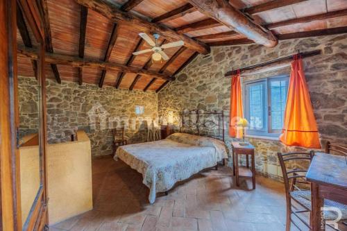 a bedroom with a bed and a table and a window at Tuscan house, exclusive pool, private garden in Bagni di Lucca