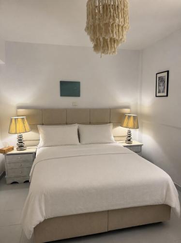 a bedroom with a large white bed with two lamps at Seaside Serenity in Komi Beach! in Kómi