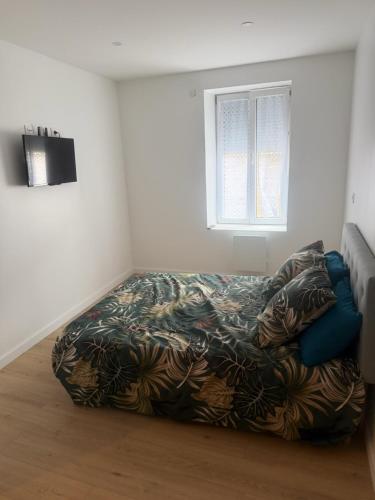 a bedroom with a bed with a blanket and a window at Maison campagne proche A75 in Vergongheon