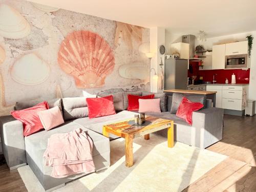 a living room with a gray couch with red pillows at Wahlheimat Haffkrug, Strandnaher Ostseeurlaub, Terrasse, Tiefgarage und WLAN in Scharbeutz