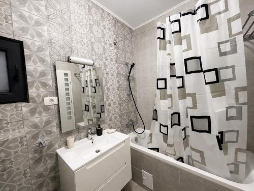 a bathroom with a sink and a shower curtain at Eqinox apartments in Mamaia Sat/Năvodari