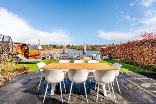 a table and chairs on a patio next to a body of water at Strandvilla met sauna in Westerhaar-Vriezenveensewijk