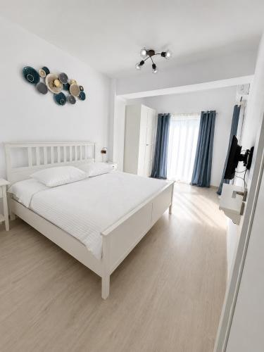 a white bedroom with a white bed and a television at Eqinox apartments in Mamaia Sat/Năvodari