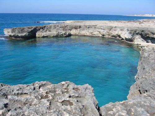 a large pool of blue water on a rocky beach at Complesso Gardencasa in Torre Suda