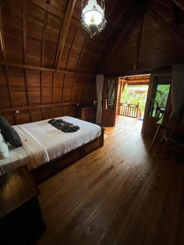 a bedroom with a bed and a wooden floor at Kawandini Homestay in Sidemen