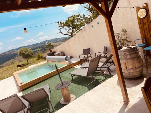a patio with a pool and chairs and a barrel at Le QG chez Flo et David in Saint-Julien-Molin-Molette