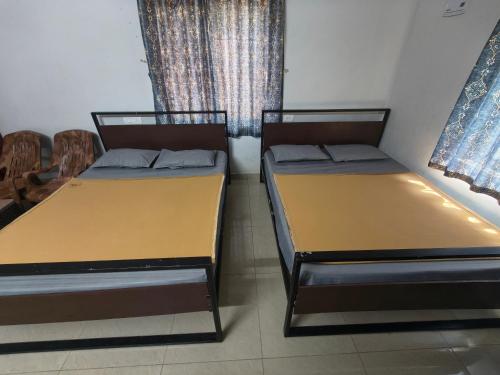 two beds in a small room with a window at Shyams homestay MV in Malpe