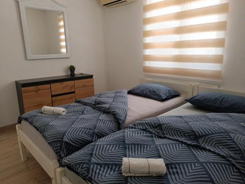 two beds in a bedroom with a dresser and a mirror at Apartman Ramljak in Prozor