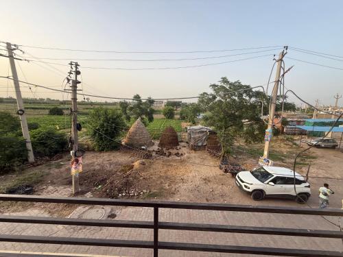 a white car parked on a dirt road with trees at AC Room with attached bathroom and kitchen access in Zirakpur