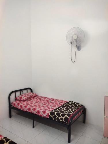 a small bed in a room with a fan at Angah Homestay in Kampong Chabang