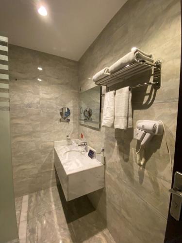 a bathroom with a white sink and a towel rack at Skoop Jeddah in Jeddah