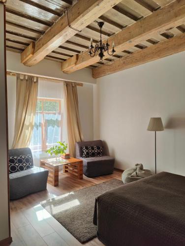 a bedroom with a bed and two chairs and a table at Viesu Nams Vilhelmīne in Līgatne