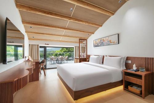 a bedroom with a large white bed and a desk at Jun hade on hillside in Hangzhou