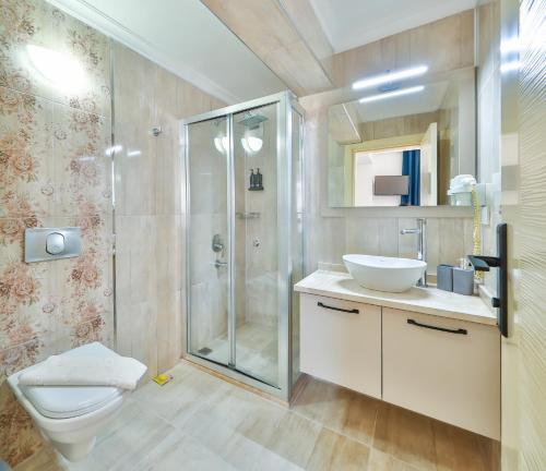 a bathroom with a shower and a toilet and a sink at The Kaş Otel in Kaş