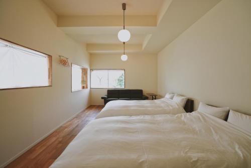 a bedroom with two beds and a chair in it at sunroom Hotel,Cafe,Bar in Miyazaki