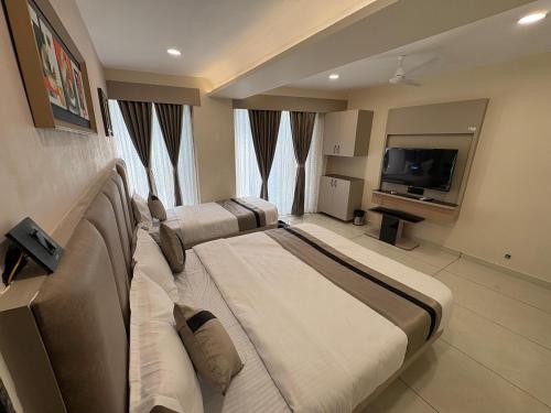 a hotel room with two beds and a flat screen tv at Hotel Prominent Town in Ahmedabad