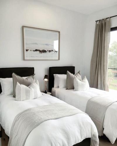 two white beds in a room with a window at Beautiful Brighton in Melbourne